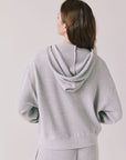 Back view of woman wearing the Abilene Light Heather Grey Zip Up Hoodie with matching pants on a white background