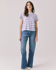 Full body view of woman wearing Chaser’s Cosmo Pink Stripes Tee paired with blue jeans on a white background