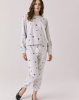 Full body view of woman wearing Chaser’s Festive Stars Pullover in Light Grey with star patterns and matching Festive Stars Joggers on a white background
