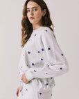 Side view of woman wearing Chaser’s Festive Stars Pullover in Light Grey with star patterns on a white background