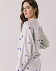 Back view of woman wearing Chaser’s Festive Stars Pullover in Light Grey with star patterns on a white background