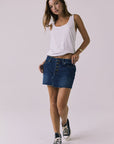 Full body front view of the Chaser Sloane Indigo Wash Mini Skirt featuring a button-front design and raw hem