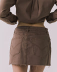 Back view of the Chaser Sloane Mini Skirt in Cognac Wash highlighting pocket placement and raw hem finish