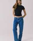 Full body view of the Chaser Louis Black Tee styled with relaxed denim jeans on a plain background