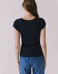 Back view of a woman wearing the Chaser Anchor Black Tee with buttons and blue jeans against a plain background