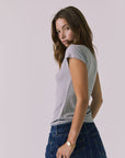 Back view of a woman wearing Chaser's heather gray button-up Anchor Tee and the Sloane Mini Skirt against a plain background