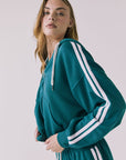 Chaser Abilenee Teal Zip Up with White Stripes in a side profile studio shot emphasizing the relaxed drape and arm stripes