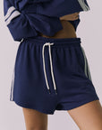 Front view of a woman wearing Chaser's navy blue Cornell Sapphire & Heather Grey Hanoverr shorts on a plain background