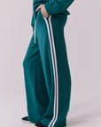 Saltwater Luxe Sandi Joggers in Teal with White side stripes shown from the side emphasizing the straight leg silhouette and sporty contrast trim with the matching Cornell Pullover partially visible