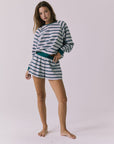 Full body view of woman wearing Chaser's Resort Stripe Long Sleeve pullover sweater and matching shorts against a plain background