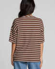 Back view of a woman wearing the Chaser Peri Nutty Brown Stripe Tee and jeans on a neutral background