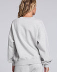 Model wearing Chaser's Fa La La La Pullover in Heather Grey with oversized red Fa La La La lettering, back view