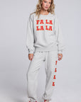 Model wearing Chaser's Fa La La La Pullover and matching Fa La La La Jogger in Heather Grey with bold red holiday lettering, full-body view