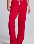 Model wearing Chaser's Cherry Bomb Delilah Track Pants in Cherry Bomb red wide-leg track pants with contrast side stripes, front view