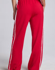 Model wearing Chaser's Cherry Bomb Delilah Track Pants in Cherry Bomb red wide-leg track pants with contrast side stripes, back view