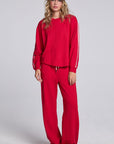 Model wearing Chaser's Cherry Bomb Delilah Track Pants and matching Anastasia Long Sleeve in Cherry Bomb with contrast stripes, full-body view