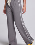 Model wearing Chaser's Soft Graphite Delilah Track Pants in Soft Graphite grey wide-leg track pants with contrast side stripes, angled view