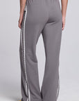Model wearing Chaser's Soft Graphite Delilah Track Pants in Soft Graphite grey wide-leg track pants with contrast side stripes, back view