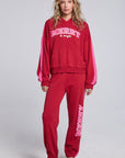 Model wearing Chaser's Merry and Bright Hoodie and matching Merry and Bright Jogger in Cranberry Velvet with holiday lettering, full-body view