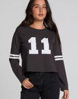 Front view of a woman wearing the Chaser 11 Long Sleeve and black jeans on a neutral background with thumb in pocket