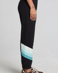 Side view of a woman wearing the Chaser Ada Black Jogger on a neutral background with arms at sides and sneakers