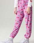 Side angle view of a girl wearing the Chaser Allover Sweethearts Girls Jogger on a neutral background with sneakers