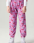 Front view of a girl wearing the Chaser Allover Sweethearts Girls Jogger on a neutral background with sneakers and shirt