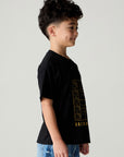Side view of a boy wearing the Chaser Basketball Boys Tee on a neutral background and pants