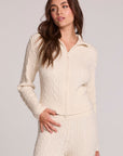 Front view of a woman wearing the Chaser Beatrix Antique White Sweater on a neutral background with white pants