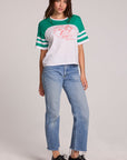 Full body front view of a woman wearing the Chaser Biker Rider Graphic Tee and blue jeans on a neutral background with both hands at sides