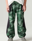 Front view of a boy wearing the Chaser Blocked Camo Pants Boys Jogger on a neutral background with white tee and sneakers