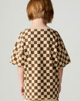 Back view of a boy wearing the Chaser Boys Solara Check Tee on a neutral background with pants
