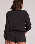 Back view of a woman wearing the Chaser Cashbah Black Pullover on a neutral background with matching black shorts