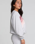 Side view of a woman wearing the Chaser Cashbah Heather Grey Pullover and pants on a neutral background