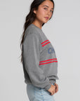 Side angle view of a woman wearing the Chaser Chicago Sweatshirt on a neutral background with hands on pickets