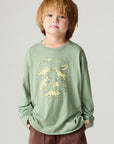 Front view of a boy wearing the Chaser Dino Action Boys Tee on a neutral background with hands in pockets of pants