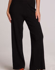 Front view of a woman wearing the Chaser Eliza Black Pants and sneakers on a neutral background