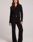 Full body front view of a woman wearing the Chaser Eliza Black Pants and matching zip up on a neutral background