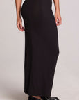 Side view of a woman wearing the Chaser Eloyse Black Maxi Skirt and black shoes on a neutral background