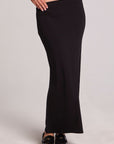 Front view of a woman wearing the Chaser Eloyse Black Maxi Skirt and black top on a neutral background