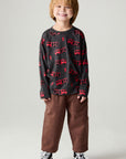 A full body front view of a boy wearing the Chaser Fire Trucks Boys Tee on a neutral background with brown pants