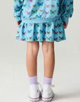Back view of a girl wearing the Chaser Flutter Pop Girls Skirt on a neutral background