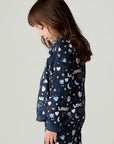 Side view of a girl wearing the Chaser Free Draw Girls Tee and pants on a neutral background