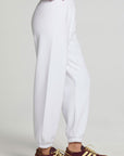 Side view of a woman wearing the Chaser High Spirits Pants on a neutral background and arms in pockets