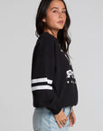 Side view of a woman wearing the Chaser I Love Sports Sweatshirt on a neutral background with jeans and hands on pockets