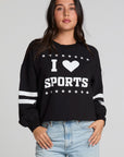 Front view of a woman wearing the Chaser I Love Sports Sweatshirt on a neutral background with hands on pockets