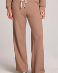 Front view of a woman wearing the Chaser Jorgia Camel Pants on a neutral background with shoes