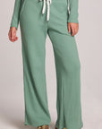 Front view of a woman wearing the Chaser Jorgia Verdelle Pants on a neutral background with green shirt