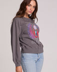 Side view of a woman wearing the Chaser Journey 1983 Tour Sweatshirt on a neutral background with bluejeans