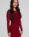 Side angle view of a woman wearing the Chaser Kevin Deep Berry Longsleeve on a neutral background with red skirt